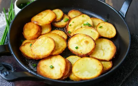 Goldbraune Bratkartoffeln mit Salz und Schnittlauch in einer Pfanne. Ein einfaches Bratkartoffeln Rezept für jeden Tag.