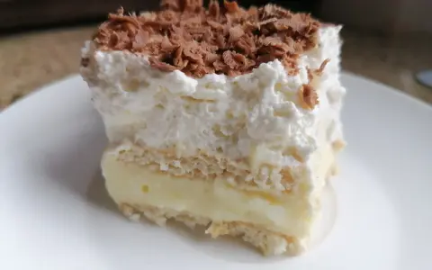 Szybkie ciasto z budyniem i bitą śmietaną, posypane wiórkami czekolady. Idealne na deser!