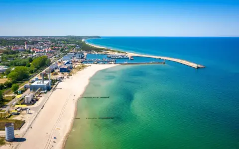 Słoneczna plaża Władysławowo z portem i turkusową wodą Bałtyku.