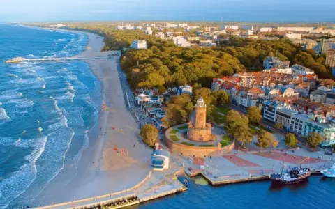 Malownicze miejscowości nad morzem z latarnią morską, plażą i portem.