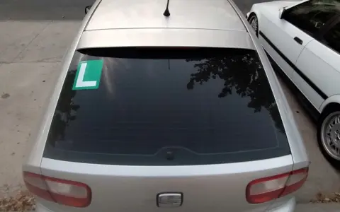 El coche plateado tiene una L verde en el lado izquierdo de la ventana trasera, indicando que el conductor está aprendiendo.
