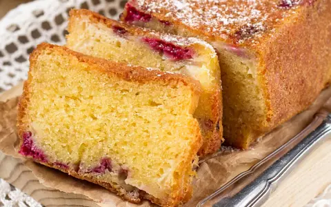 Puszyste ciasto z serka wiejskiego z malinami, posypane cukrem pudrem. Idealne na podwieczorek.