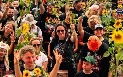 Uśmiechnięci ludzie z słonecznikami na jednym z 3 festiwali muzycznych w Polsce. Radość i pokój na twarzach.