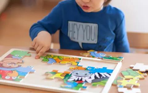 Chłopiec układa kolorowe puzzle ze zwierzątkami. Ukladanie puzzli co ćwiczy? Rozwija spostrzegawczość i zdolności manualne.
