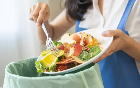 Persona separa restos de comida, como aguacate y cáscaras de manzana, para el reciclaje orgánico.