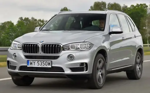 Srebrne BMW X5 E70 w ruchu. Kierowca za kierownicą. Rozpiska bezpieczników BMW X5 E70 jest kluczowa dla jego sprawnego działania.