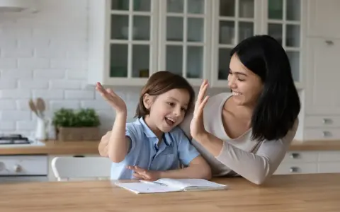 Mutter und Kind geben sich High Five. Das Kind will nicht lernen, aber die Mutter motiviert es.
