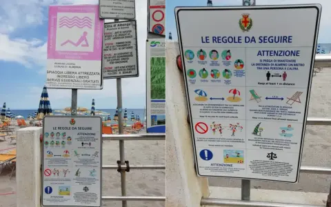 Cartelli informativi su una spiaggia libera attrezzata a Rimini, con regole per il distanziamento sociale e l'uso degli spazi.
