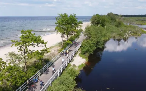 Rowerzyści przemierzają malowniczą trasę EuroVelo 10 wzdłuż plaży i spokojnej wody.
