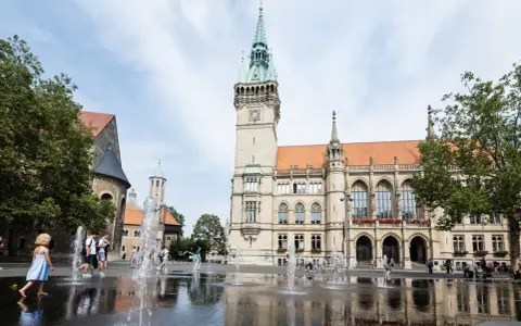 Kinder planschen im Brunnen vor dem Rathaus. Hier kann man in Braunschweig viel erleben, z.B. den Dom besichtigen.