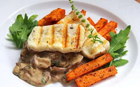 Grillowany ser halloumi z kremowym sosem grzybowym, pieczonymi batatami i rukolą.