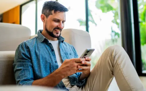 Hombre sonriente usando su móvil para bbva abrir cuenta.