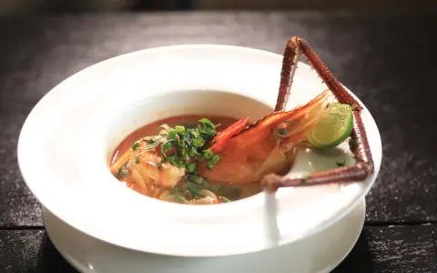 Sopa de marisco con gamba, lima y chile en plato blanco.