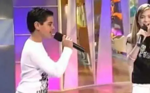 Ana Mena y Abraham Mateo, de niños, cantando con micrófonos en un escenario.