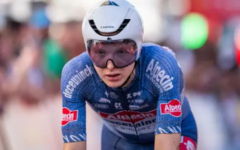 Juri Hollmann im Zeitfahr-Outfit, konzentriert auf der Strecke. Das blaue Trikot mit Alpecin-Logo und die aerodynamische Kopfbedeckung sind gut erkennbar.
