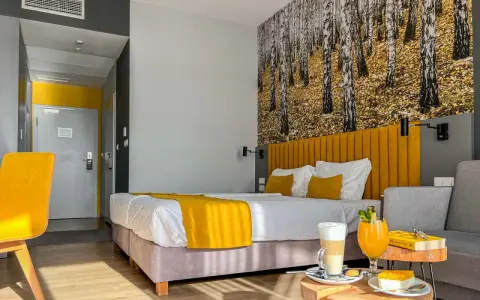 Pokój hotelowy z motywem lasu, żółtym akcentem i napojami. Idealne miejsce na relaks, jak sugerują notera hotel spa opinie.