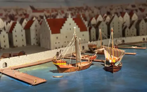 Modell av medeltida hamn i Visby. Skepp ligger vid kajen framför stadens karaktäristiska hus. En glimt av Visby historia.