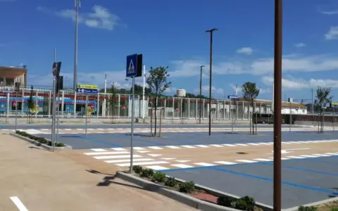 Parcheggio rimini con strisce pedonali e segnaletica, sullo sfondo un treno blu.
