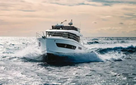 Un bateau blanc fend les vagues, le moteur de 20 cv propulsant l'embarcation à pleine vitesse.