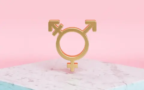 Złoty symbol trans, łączący symbole Wenus, Marsa i hermafrodyty, na marmurowej podstawie.