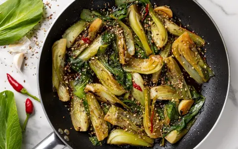 Verdure in padella, bok choy saltato con aglio, peperoncino e semi di sesamo, un piatto saporito e colorato.