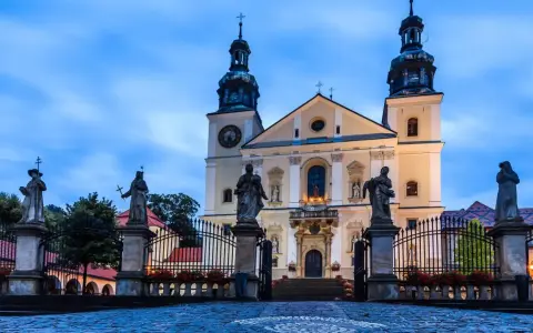 Imponująca bazylika na Kalwarii Zebrzydowskiej, z rzeźbami świętych przed bramą i wieżami w niebo.