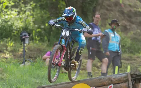 Troy Brosnan springt mit seinem Downhill-Bike über eine Holzrampe, bereit für den nächsten Sprung.