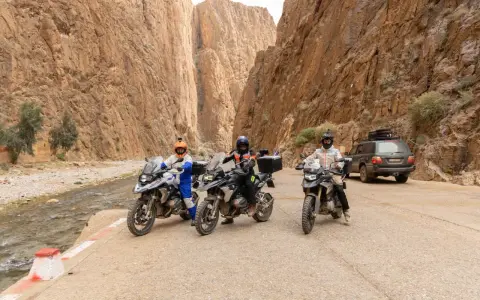 Tre moto e un fuoristrada pronti per avventurosi itinerari in moto in Marocco, tra canyon mozzafiato e un fiume.