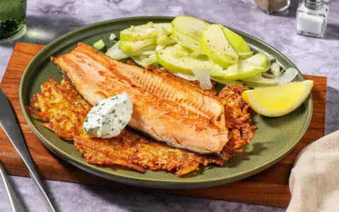 Filetto di salmone su croccanti rosti di patate, con insalata di mele e una quenelle di salsa alle erbe.
