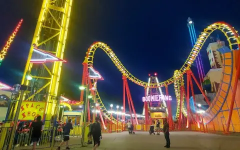 Wiedeń wesołe miasteczko nocą. Kolejka Boomerang i wieża zjeżdżalni w blasku neonów.