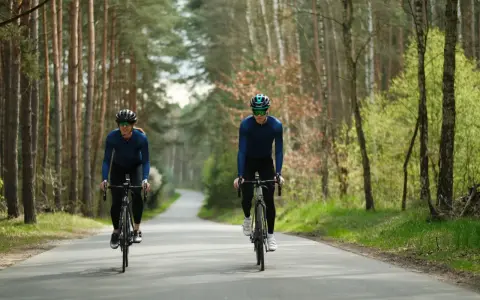 Para jazda na rowerze: kask, okulary, długie rękawy i spodnie. Dwóch rowerzystów w lesie.