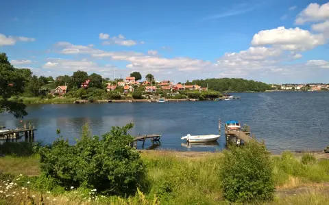 Idealny weekend w Szwecji: malownicza zatoka, czerwone domki na wzgórzu, drewniane pomosty i łodzie.