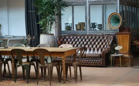 Stary gramofon i pikowana kanapa w salonie. Inspiracja, co zrobić ze starymi meblami, by nadać im nowy charakter.
