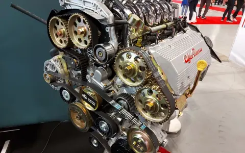 Silnik Alfa Romeo z widocznym układem rozrządu, kołami zębatymi i paskami. Widać napis "GTA 16V" i logo producenta. To serce potężnej maszyny, być może z legendarnym silnikiem hemi.
