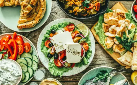 Pyszny grecki posiłek: pieczona ryba, sałatka grecka, kurczak, hummus i ciasto filo, które ma dużo węglowodanów.