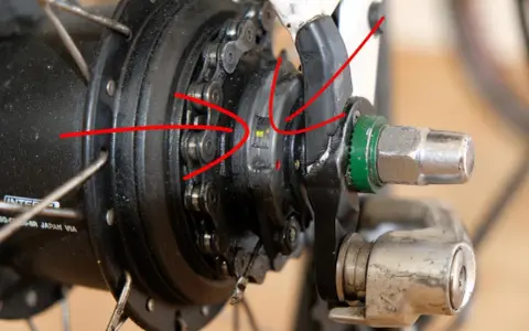 Rote Pfeile zeigen auf die Markierungen zum shimano nexus 8 einstellen. Nahaufnahme einer Nabenschaltung.
