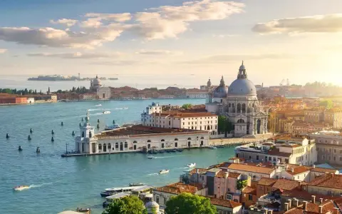 Venice cityscape with canals, boats, and historic buildings under a sunny sky.