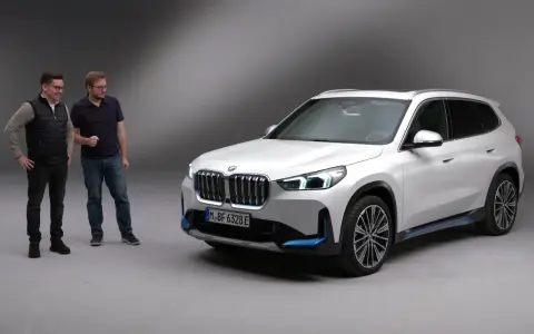 Dwóch mężczyzn stoi obok białego BMW iX1.