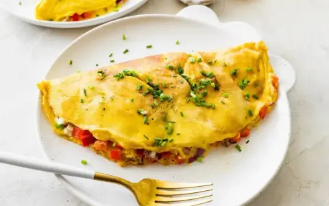 Złocisty omlet z białek, nadziany warzywami i serem, posypany szczypiorkiem. Idealny na lekki posiłek.