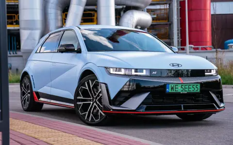 Jasnoniebieski Hyundai IONIQ 5 N z czarnymi akcentami i czerwonymi detalami, zaparkowany przed przemysłową instalacją.