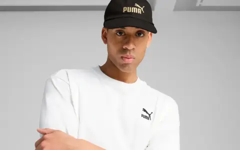 Mężczyzna w czarnej czapce z logo Puma i białej koszulce.