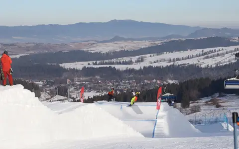 Snowboardziści na stoku, idealne miejsce, gdzie na narty z Wrocławia. W tle góry i miasteczko.