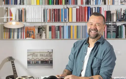 Fabio Volo sorride tra gli scaffali pieni di libri, forse in attesa di presentare il suo ultimo libro.
