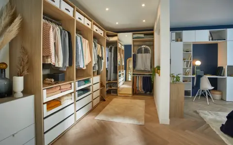 Un dressing DIY bien organisé avec des étagères en bois, des tiroirs blancs et des vêtements suspendus. Un espace fonctionnel pour ranger vos affaires.