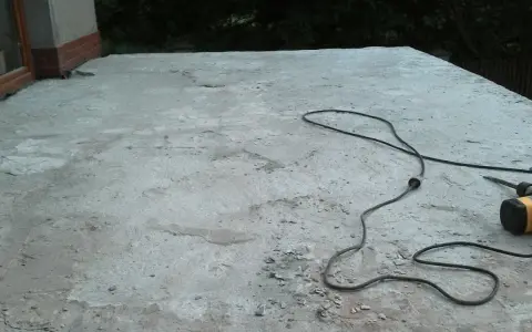 Betonowy taras czeka na remont. Obok leży młot udarowy, gotowy do pracy. Nivoplan pomoże w pracach.