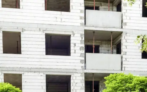 Budowa bloku mieszkalnego, widoczne puste okna i balkony. W przyszłości powstanie tu mieszkanie komunalne.