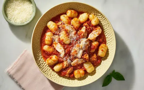 Pyszne gnocchi z kurczakiem w sosie pomidorowym, posypane parmezanem. Idealne danie dla miłośników włoskich smaków.