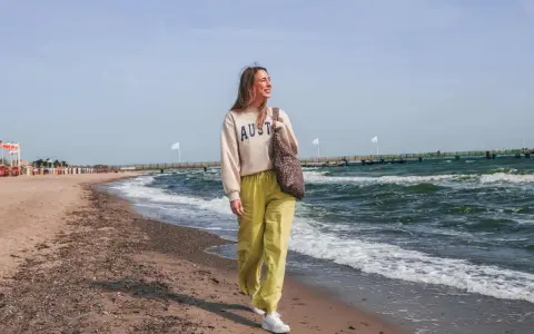 Frau spaziert am stein strand entlang, die Wellen rauschen.