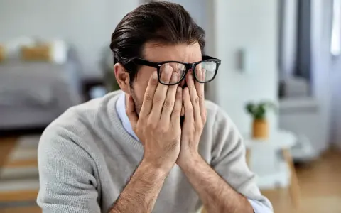 Mann mit Brille reibt sich die Augen, wirkt gestresst. Manche glauben, rauchen hilft gegen Stress, doch das ist ein Trugschluss.