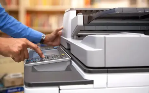 Mani che usano una stampante multifunzione, aiutando a decidere se è meglio stampante laser o inkjet per le proprie esigenze.